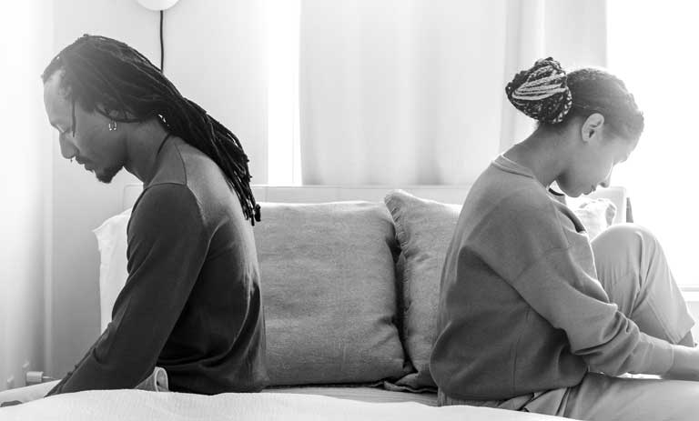 A divorcing African American couple sitting with their backs toward each other.